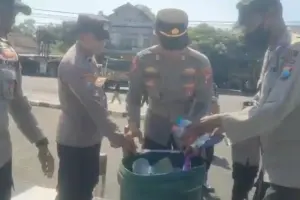Personel Polres Blitar membersihkan sampah usai mengamankan aksi Sobat MBG di Alun-Alun Kanigoro sebagai wujud kepedulian lingkungan.