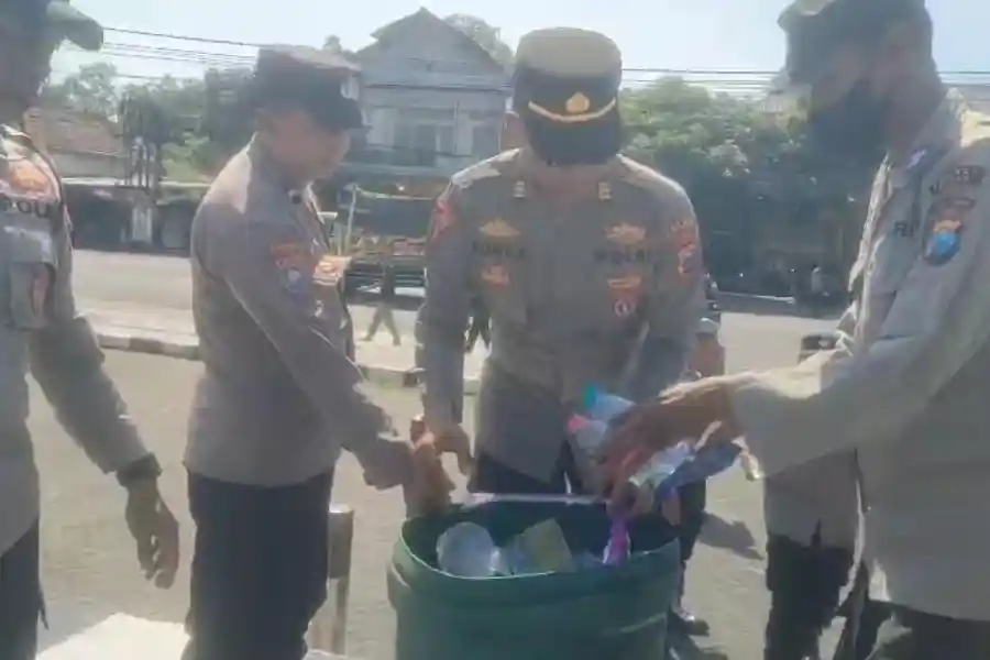 Personel Polres Blitar membersihkan sampah usai mengamankan aksi Sobat MBG di Alun-Alun Kanigoro sebagai wujud kepedulian lingkungan.